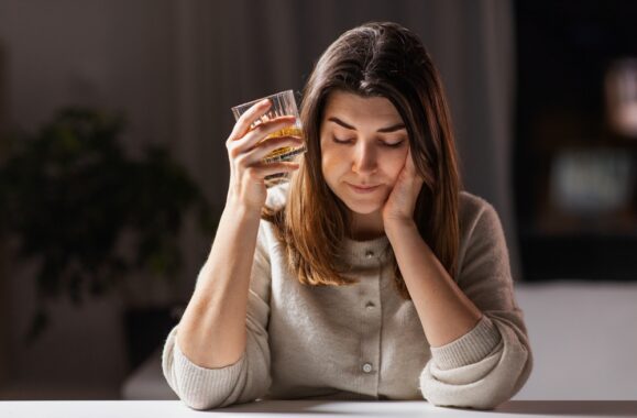 Young woman seems worried holding a glass of alcohol